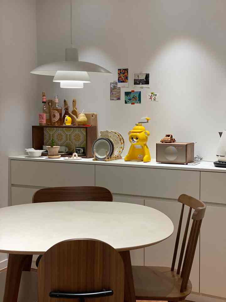 White-toned dining room featuring a ceramic table, wooden chairs, and minimal décor creating a clean atmosphere
