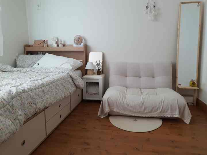 Natural tone 5-pyeong bedroom with wood floor and white walls featuring a bed and single sofa creating a cozy atmosphere