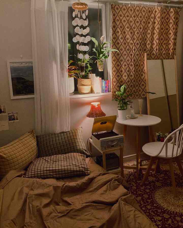 温かみのあるブラウン調の小さな寝室、チェック柄の枕と植物が配置された雰囲気のある空間