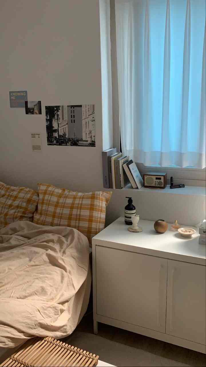 White and beige toned studio bedroom featuring yellow checkered pillows and beige duvet cover creating a cozy atmosphere
