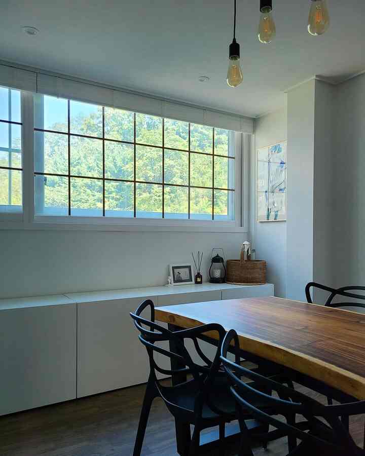 白い壁と木目テーブル、黒いダイニングチェアが配置された自然な雰囲気のダイニングルーム