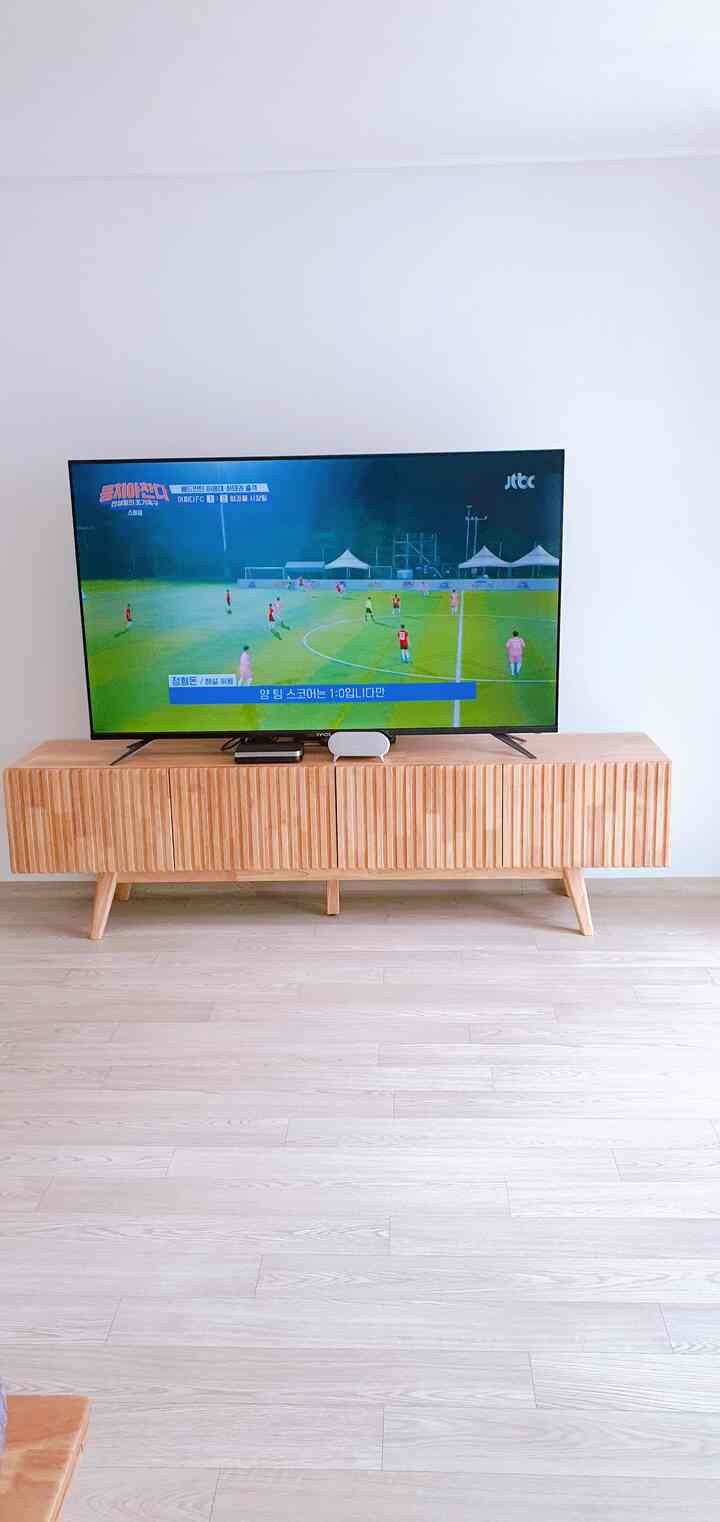 明るい木目調の床と木製テレビ台が配置されたシンプルで清潔感のあるリビングスペース