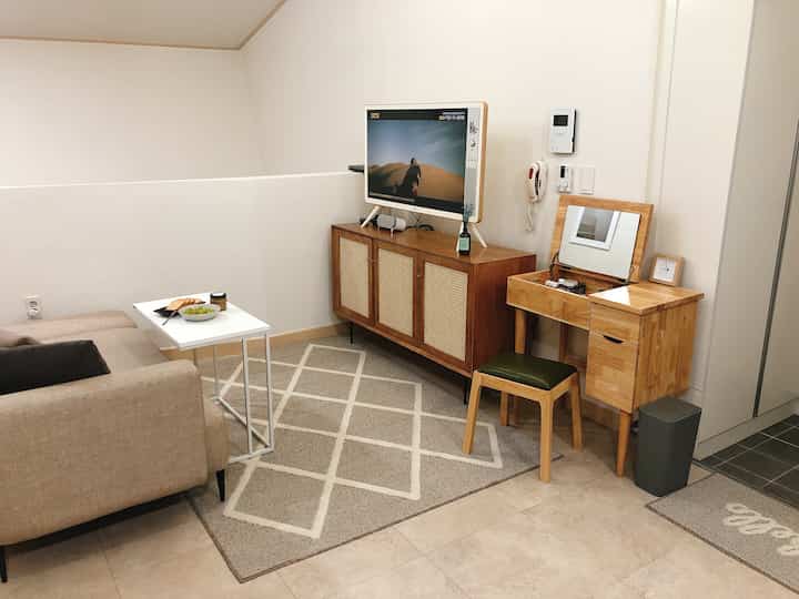 Natural color living room featuring beige sofa, wood tone TV stand and vanity with a simple modern atmosphere