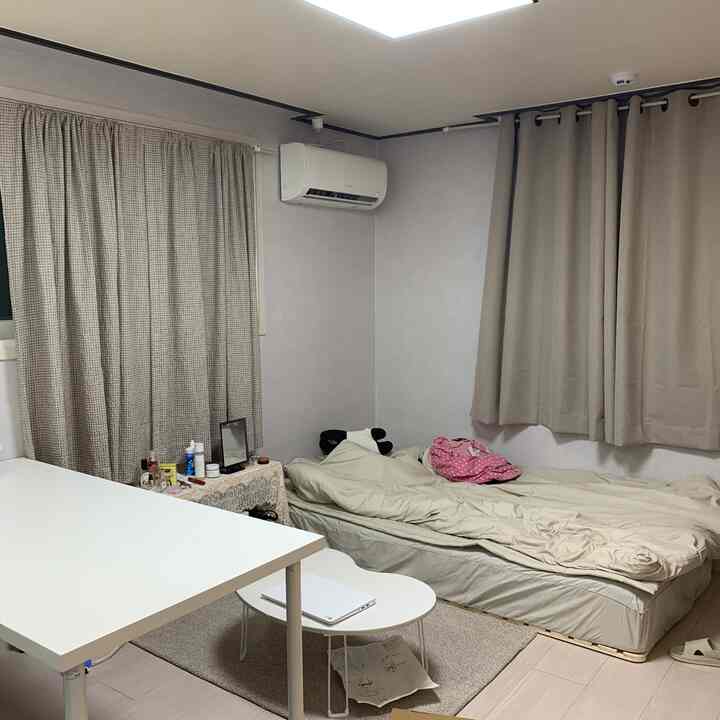 Beige-toned studio bedroom featuring a bed and desk in a cozy small room