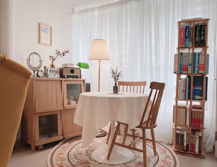 Cozy cafe-style living space with white curtains and natural wood furniture