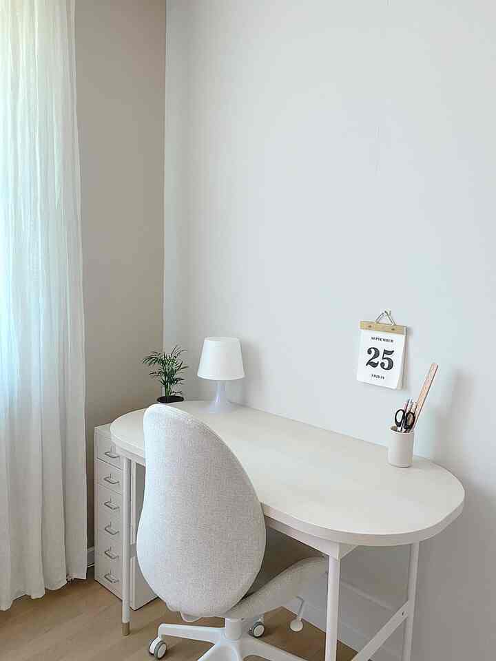 White and natural toned kids' study room featuring a desk, office chair, desk lamp, and a small plant for a clean interior