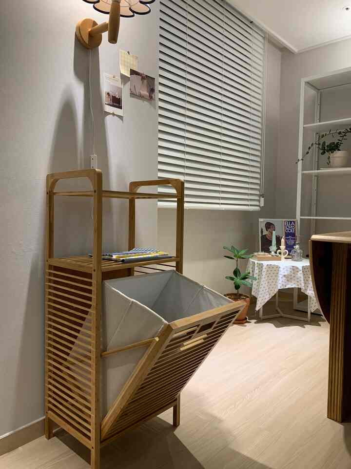 Natural living room with practical wood-tone and white laundry hamper featuring a sliding basket and shelf