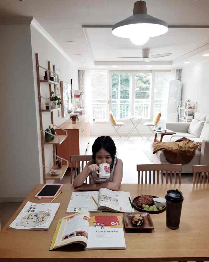 White and wood tone long and narrow living room featuring a dining table and sofa with a cozy, clean atmosphere