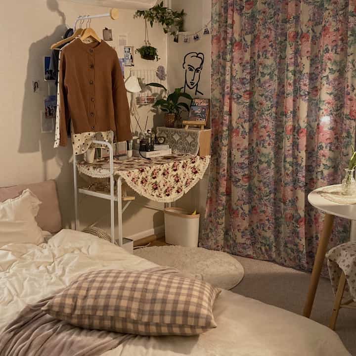 Cozy natural modern small bedroom in warm beige and pink tones featuring floral curtains and soft bedding