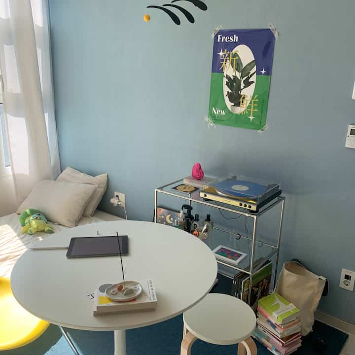 Cozy compact blue-walled space featuring a white round dining table, stool, yellow chair for a single household home cafe setup