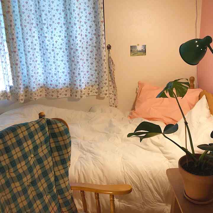 ホワイトとピンクの色調の寝室、花柄カーテンとヴィンテージの木製ベッドが配置された温かみのあるインテリア