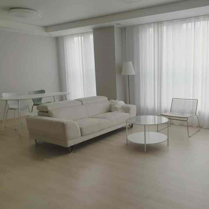 Natural modern living and dining room in white and beige tones, featuring a modern sofa, coffee table, and armchair