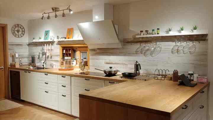 ホワイトの壁と木目調のカウンターがあるキッチン、壁にはヴィンテージ風の時計が掛けられている