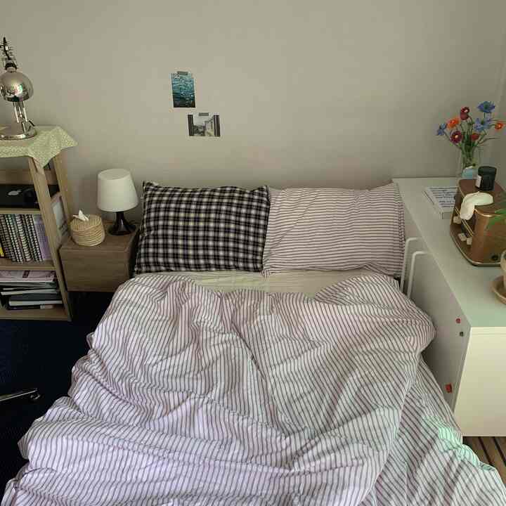 White and navy toned studio bedroom featuring striped bedding and wooden furniture in a cozy, simple space