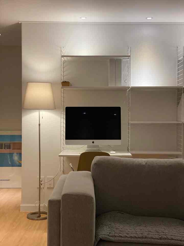 White and gray-toned home office space featuring desk and sofa with simple Nordic-style interior