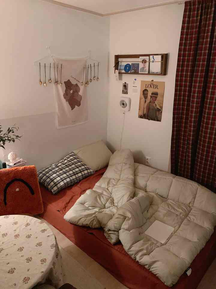 ベージュのナチュラルトーンの寝室、壁棚とポスターが配置された居心地の良い空間