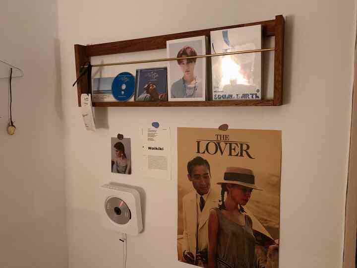 A cozy space with white walls and wood-toned wall shelf displaying vintage movie posters and an analog CD player