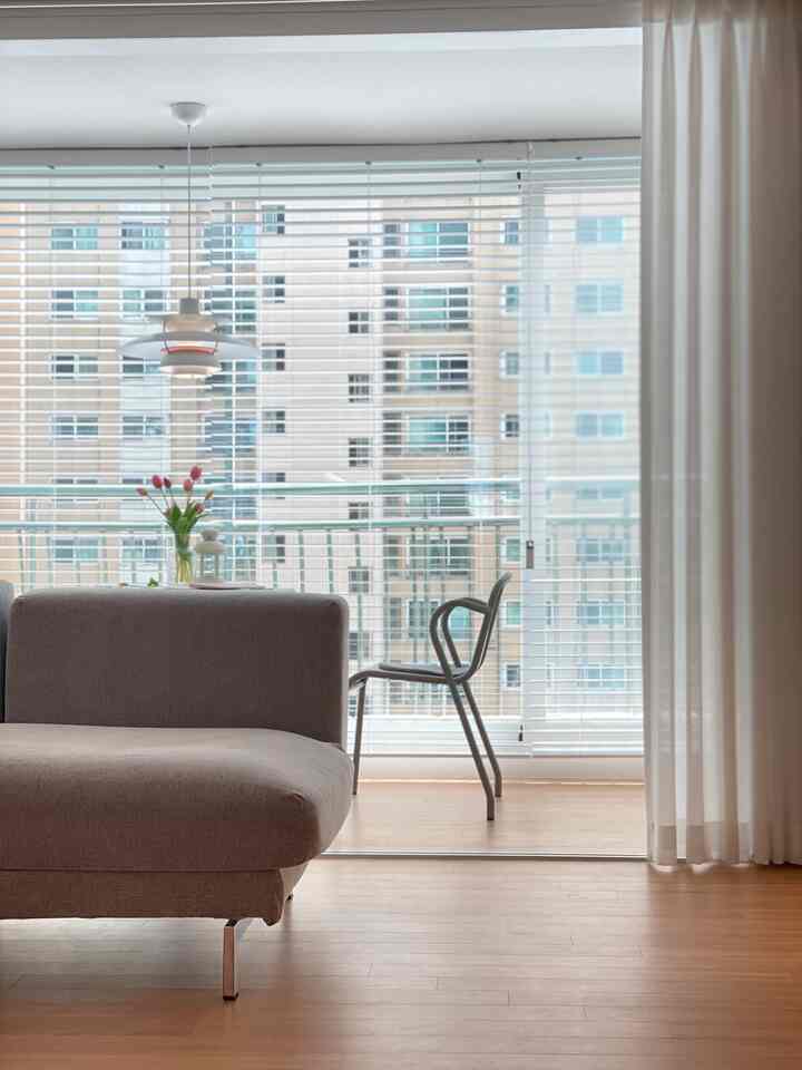 White and wood tone floor living room adjacent to veranda, featuring simple gray sofa and pendant lighting in Nordic style