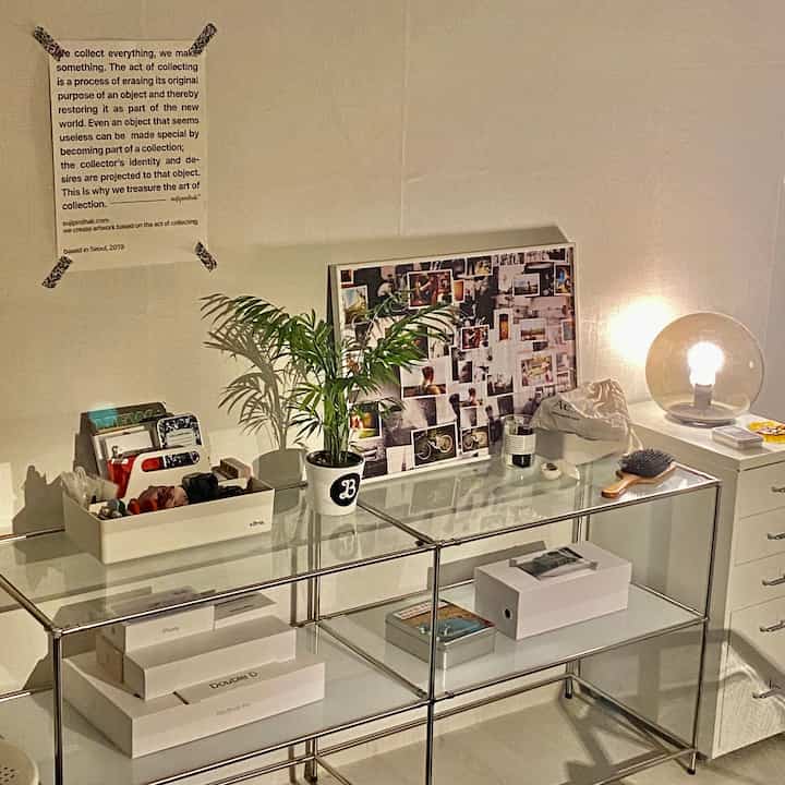 Warmly lit white-tone studio home office featuring modular furniture, plant, and simple decor