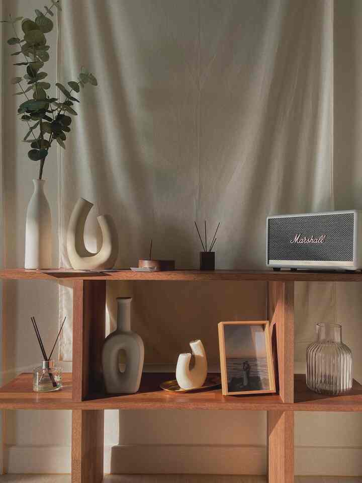 A warm wood tone natural wooden cabinet featuring simple ceramic vases and decorative objets creating a cozy decorative space