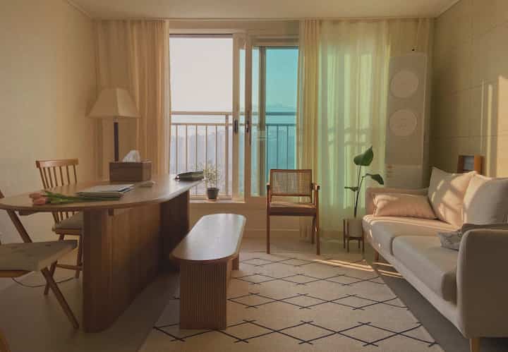 温かみのあるナチュラルトーンのコンパクトなリビングとダイニング、木製テーブルとアイボリーソファが配置された雰囲気のある空間