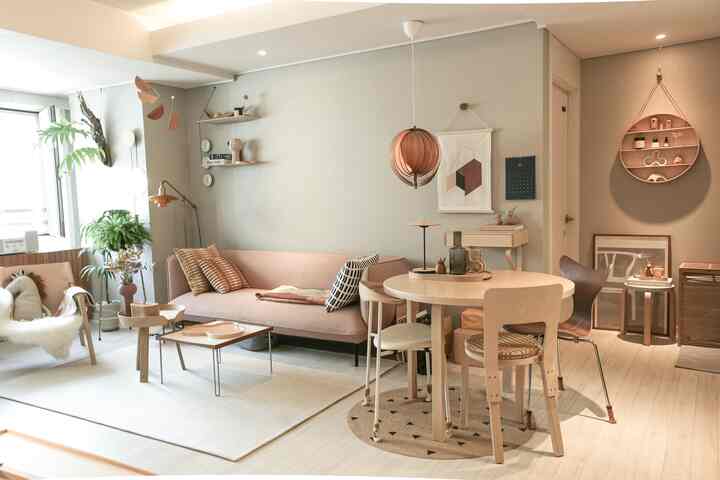 Natural tone and wood-toned Nordic living room featuring a pink sofa and round dining table with warm, cozy atmosphere