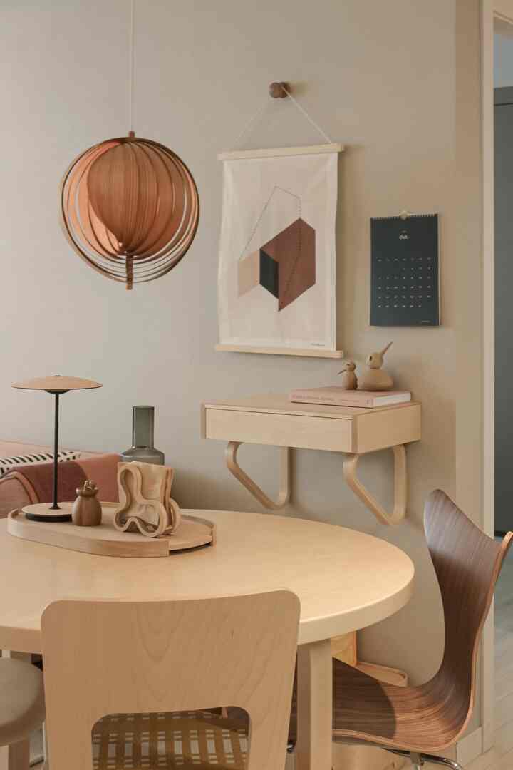 Natural color toned dining space featuring a wooden round table, pendant light, and geometric poster creating a clean dining room