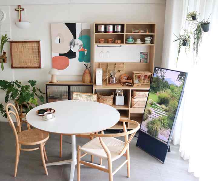 White and wood-toned dining room featuring a round table and rattan chairs in a cozy home cafe setting