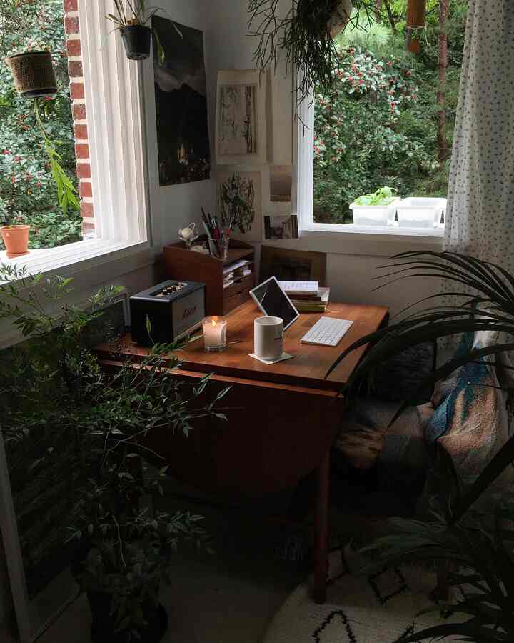 Cozy home office with brown wood tone desk and green plants by the windows