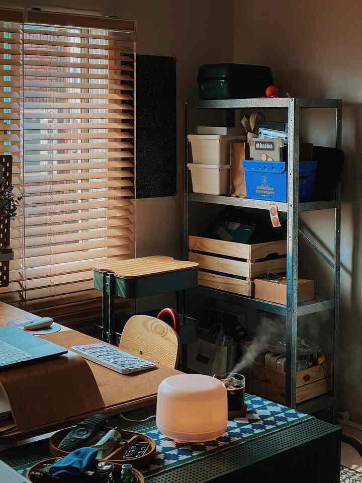 Natural tone studio apartment workspace featuring storage shelves and diffuser with cozy atmosphere