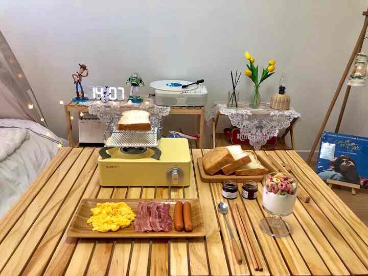 白い壁と木目調のダイニングテーブルが配されたワンルーム寝室、朝のホームカフェの雰囲気を演出するインテリア