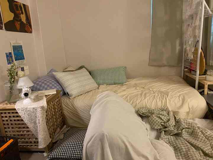 ナチュラルなベージュとホワイトトーンのワンルーム寝室、枕と居心地の良いベッドが配置された印象的な空間