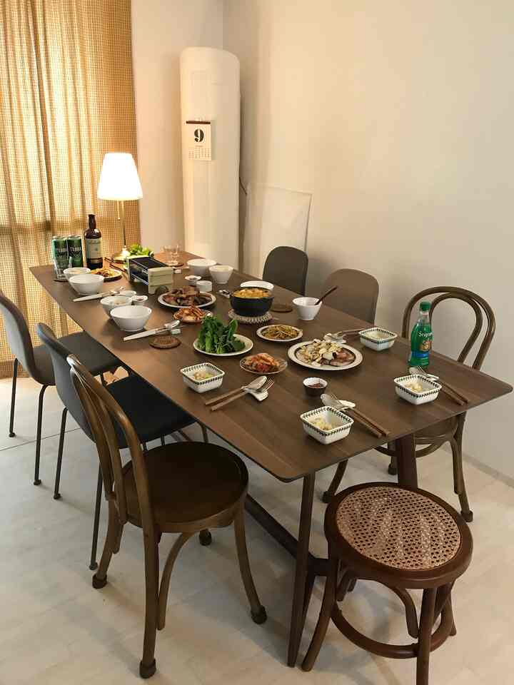 Natural brown-toned spacious living dining room featuring 8-person dining table with assorted chairs in a warm dining setting