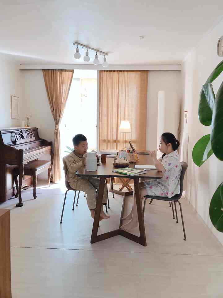 A living room dining space featuring soft beige and brown tones, with children sitting comfortably at the table