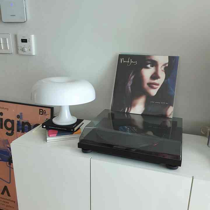Simple home cafe space with black turntable and modern white lamp on white cabinet