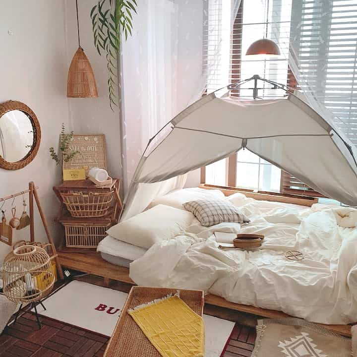 Natural-tone bedroom featuring wooden bed, heating tent, and rattan decor creating a cozy atmosphere
