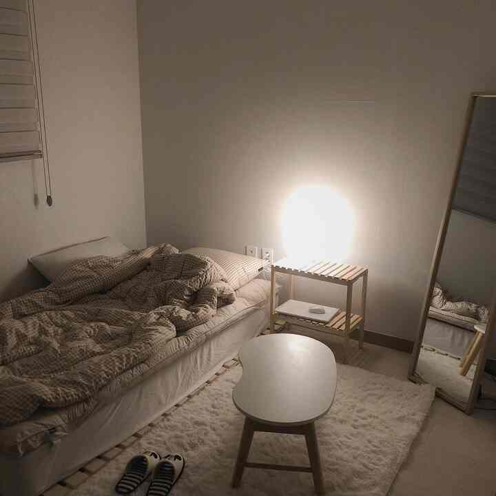 Beige and wood tone studio bedroom featuring minimal furniture and warm lighting creating a cozy atmosphere