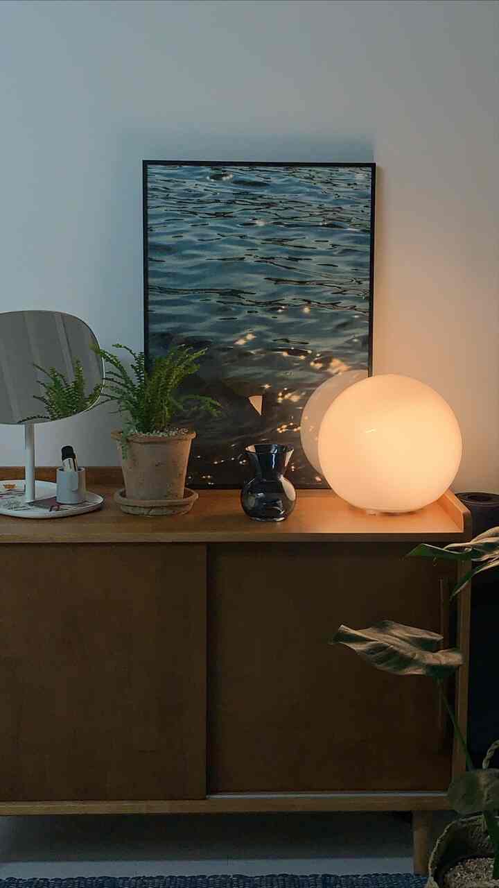 Cozy space with pastel-toned walls featuring vintage-style cabinet, round lamp lighting, and plants