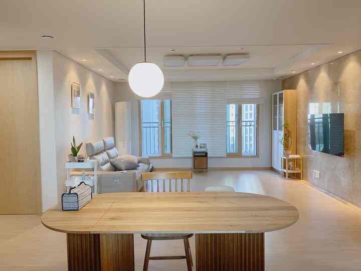 Bright white and wood tone 4-person living and dining room featuring pendant light and sofa in a natural setting
