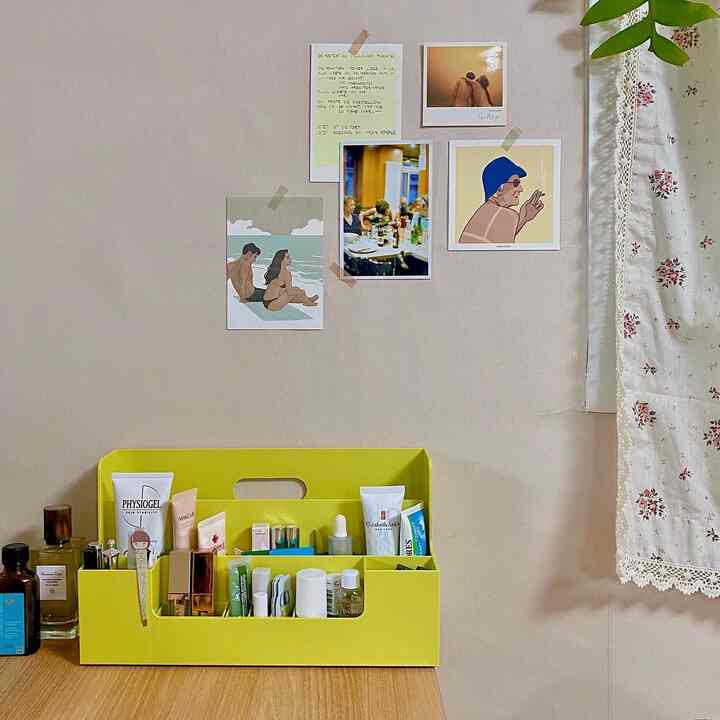Yellow-toned desk featuring an organized cosmetic storage box with natural wall backdrop, creating a tidy and cozy atmosphere