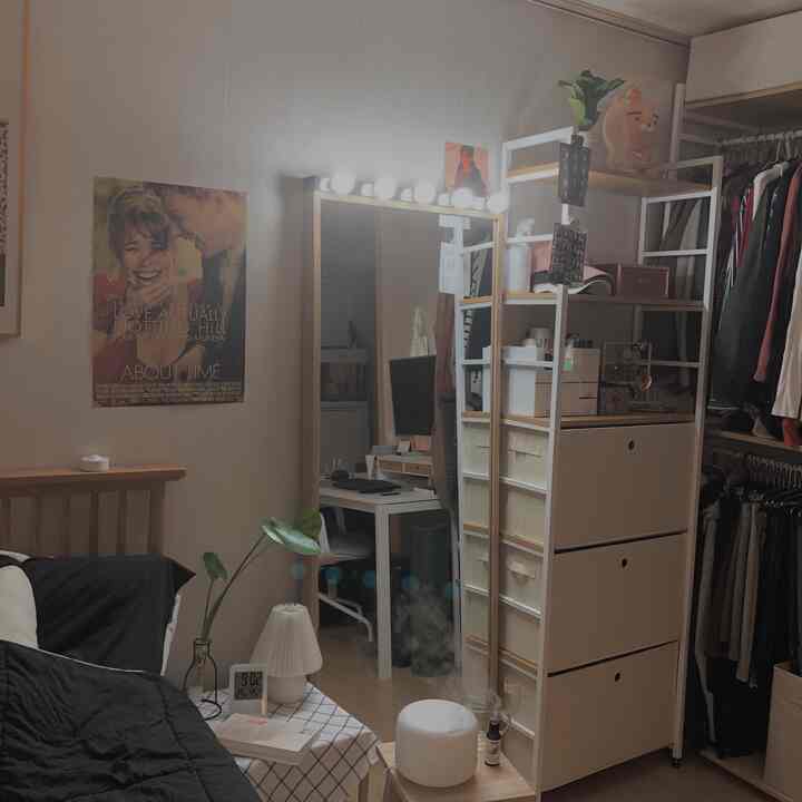 White-toned walk-in closet and bedroom space featuring a full-length mirror and vanity lighting with a cozy atmosphere