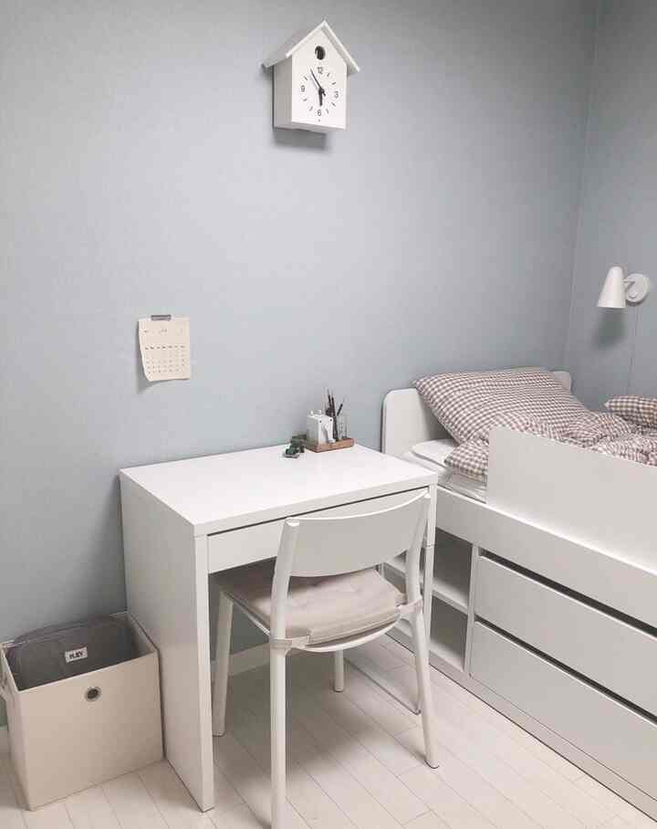 Minimal white and gray toned kids' room featuring bed frame and desk with a clean organized atmosphere