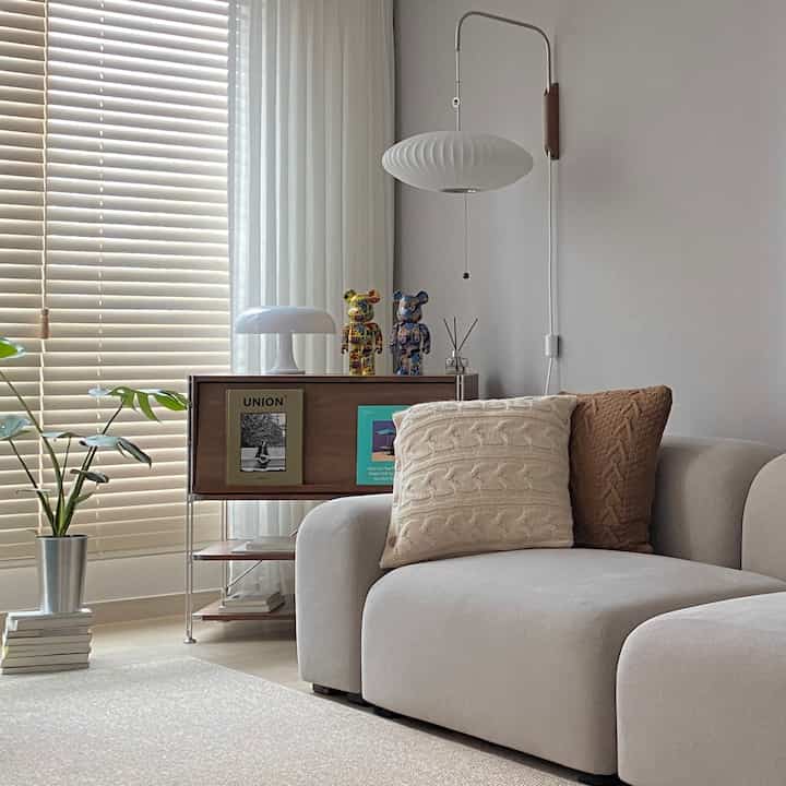 Natural beige-toned living room featuring a beige sofa and wooden cabinet with a cozy atmosphere