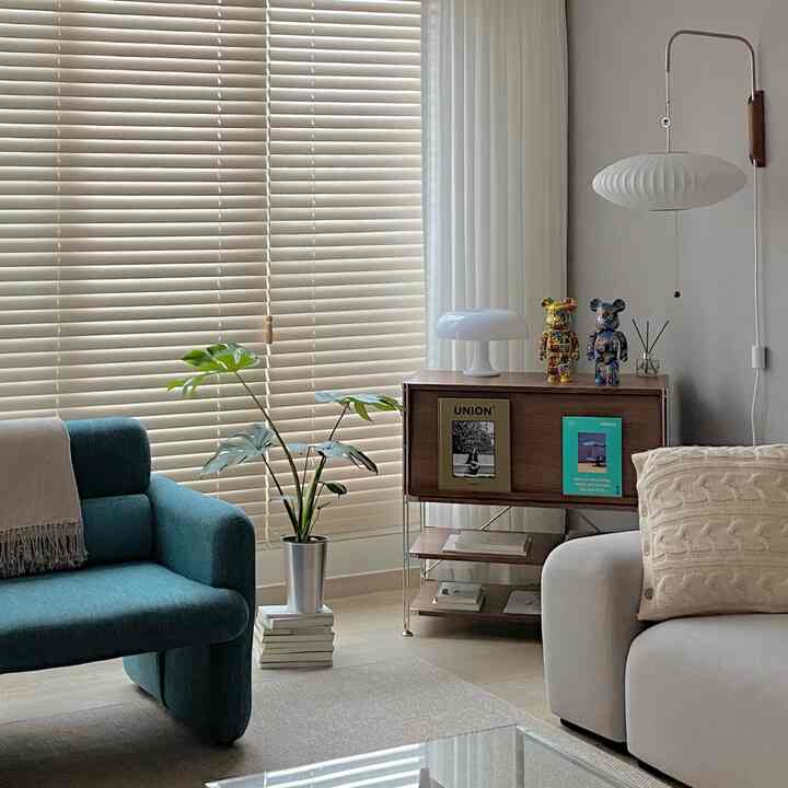 ホワイトのブラインドと木目調の家具、ネイビーブルーのソファが配置されたナチュラルな雰囲気のリビング