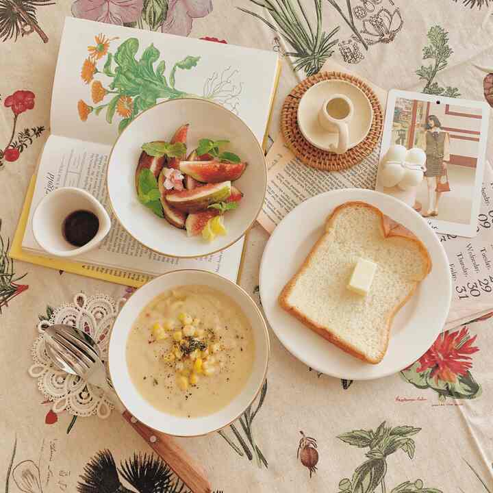 Natural toned home cafe table featuring bread, soup bowls, and fruit plating on floral tablecloth creating cozy autumn vibe