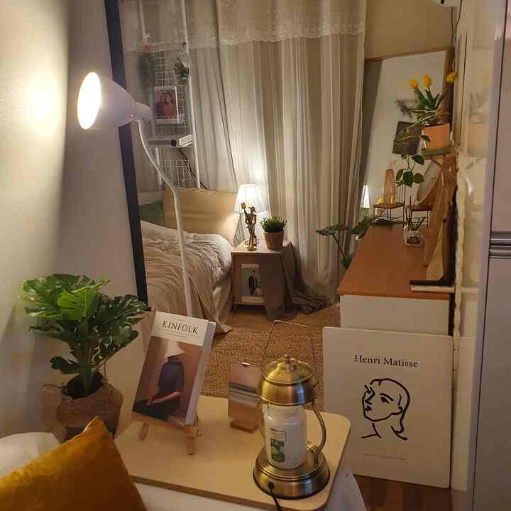 Cozy narrow bedroom in warm beige and wood tones featuring bed, nightstand, and plants creating a natural ambiance