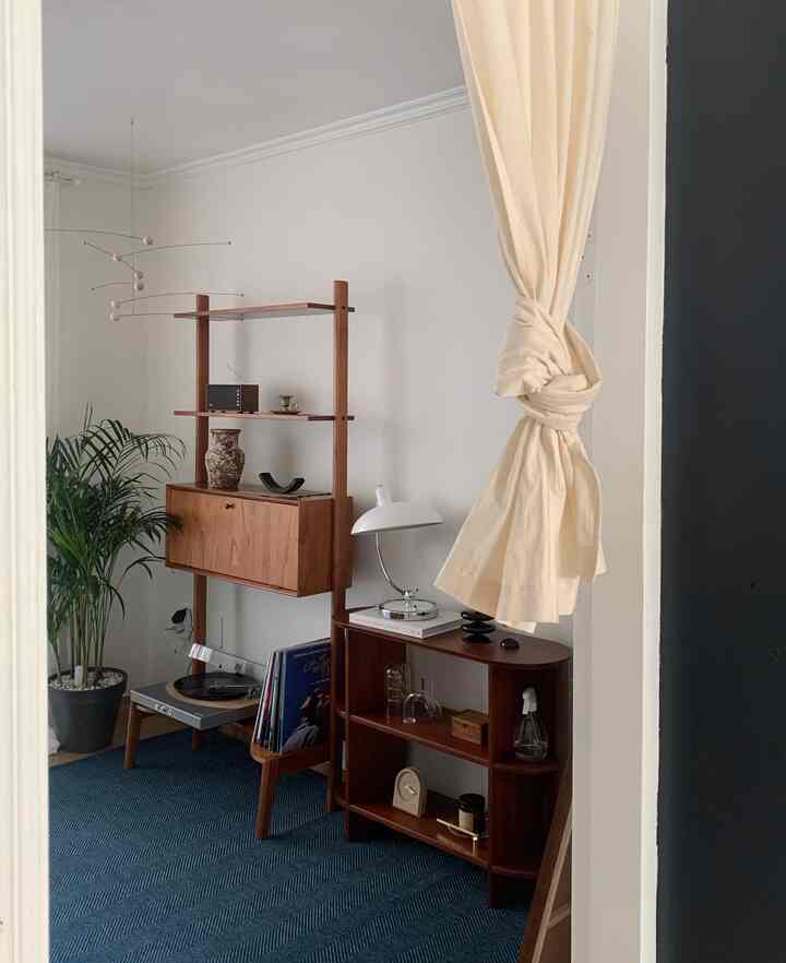 ネイビーカーペットと木目調家具が配置された北欧スタイルのリビング、自然で落ち着いた雰囲気のあるインテリア