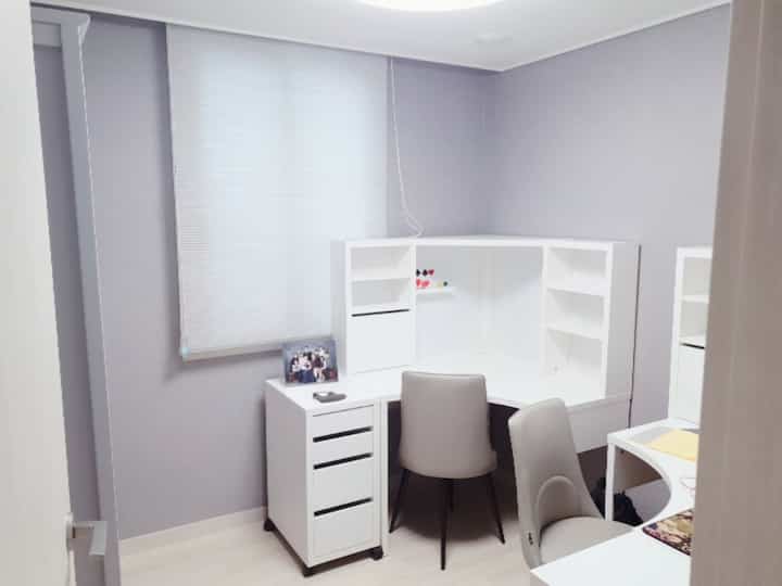 Small study space in white tone featuring a corner desk and armchairs arranged neatly for practical work setup