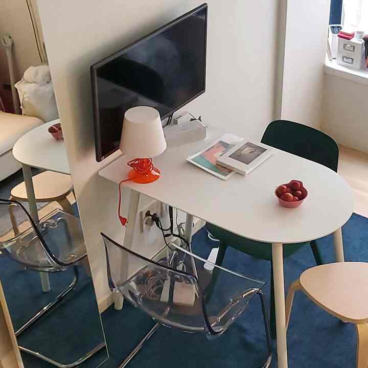 Modern minimalist living room in white and sky blue tones featuring transparent chairs and a white oval table