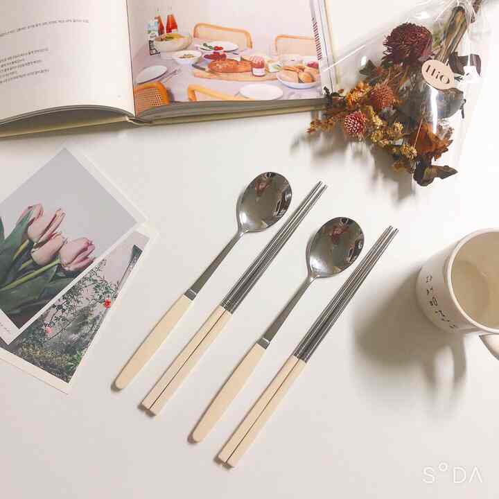 White-themed kitchen table featuring ivory-handled cutlery and a cup in a neat home cafe atmosphere